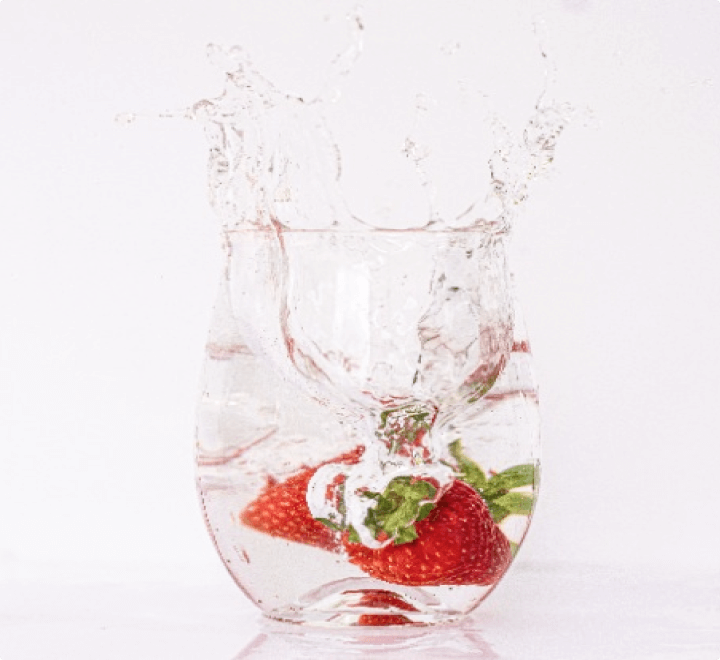 コップの中の水にイチゴが二つ入っている写真